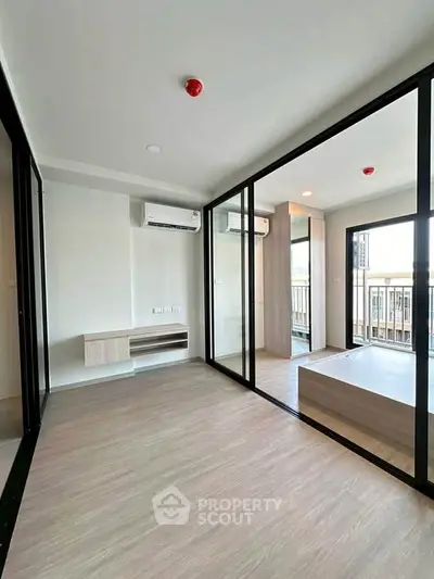 Modern apartment interior with glass partitions and balcony view, featuring sleek air conditioning units.
