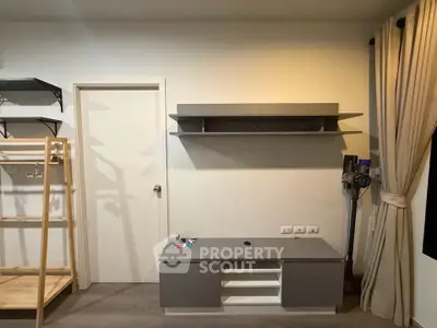 Modern living room with sleek storage unit and wall-mounted shelf, featuring minimalist design and neutral tones.