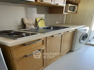 Modern kitchen with wooden cabinets, washing machine, and electric stove