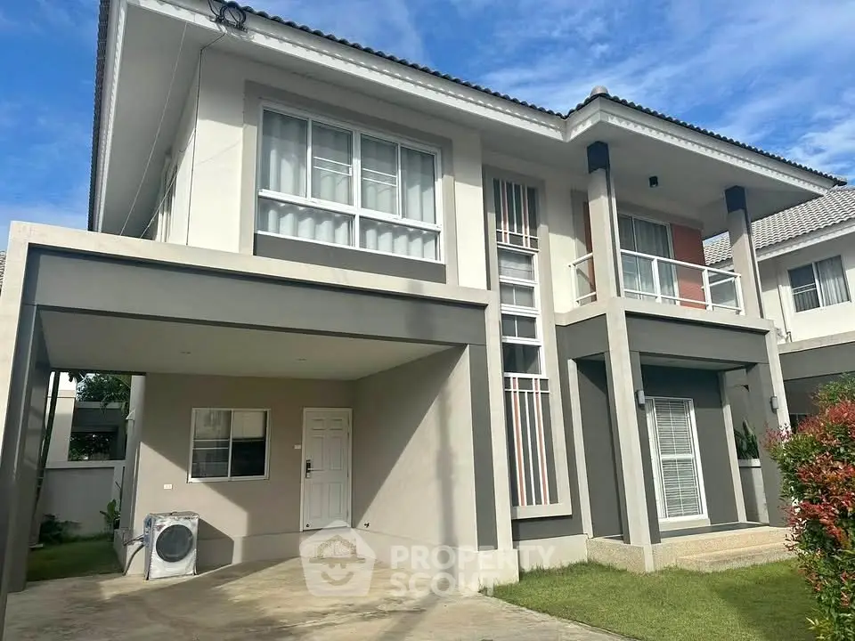 Modern two-story house with carport and large windows under a clear blue sky.