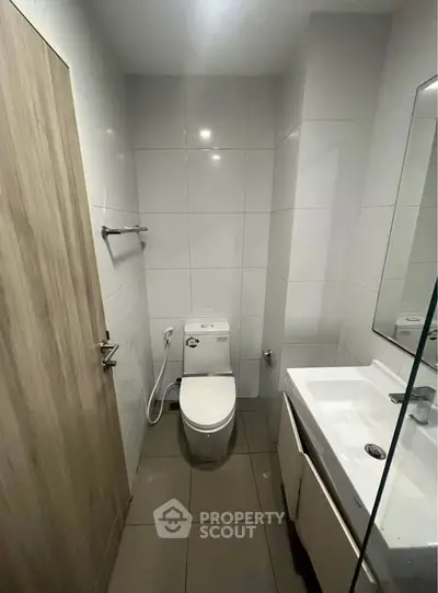 Modern bathroom with sleek fixtures and minimalist design, featuring a toilet and sink.