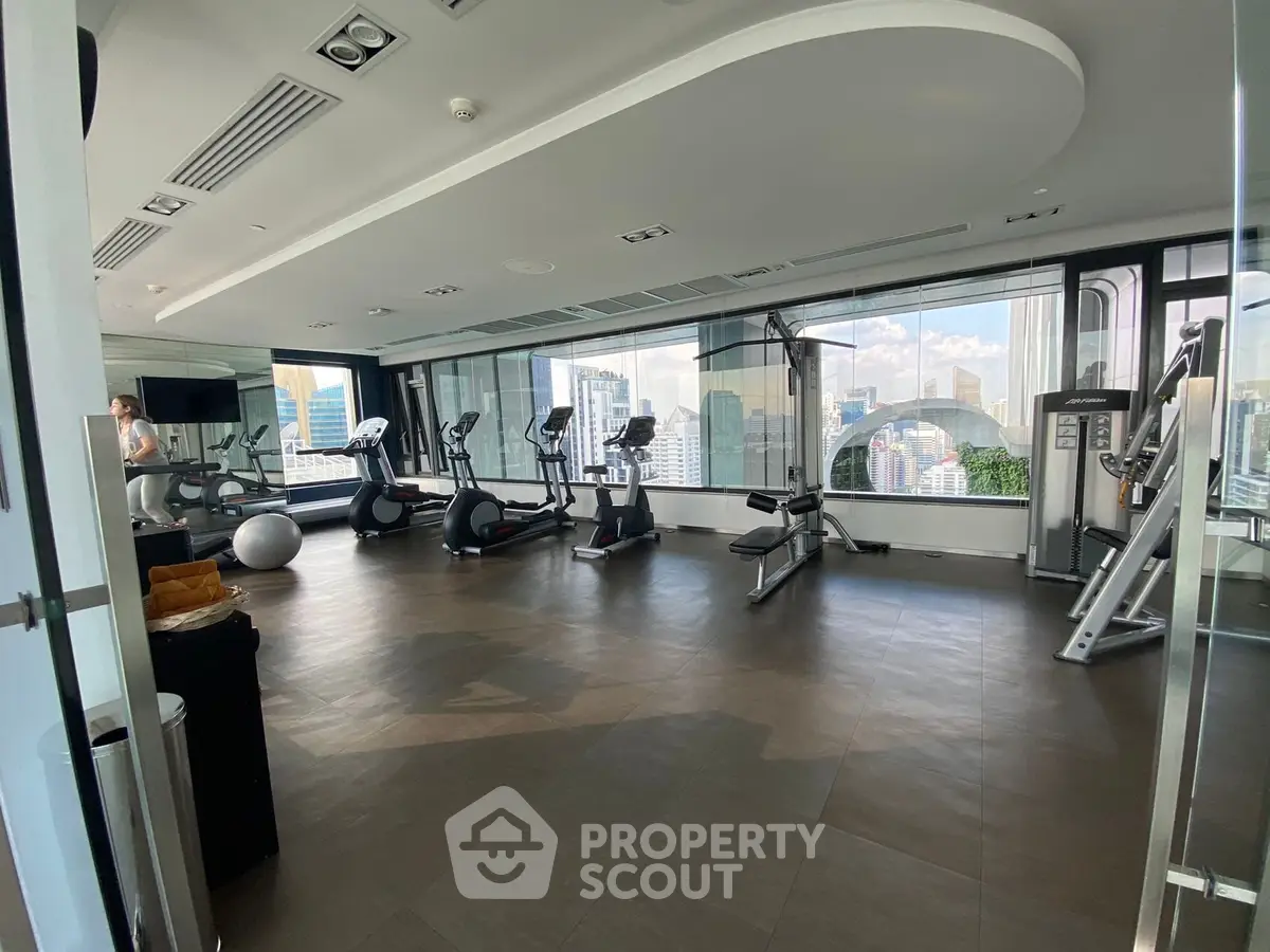 Modern gym with city view and state-of-the-art equipment in luxury high-rise building.