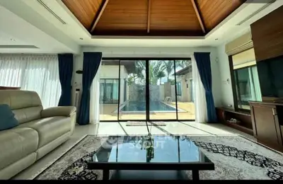 Luxurious living room with pool view, high wooden ceiling, and elegant decor in a modern villa.