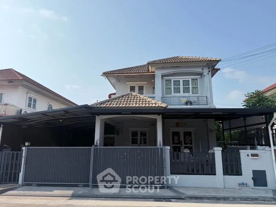 Charming two-story house with tiled roof and spacious gated driveway in a serene neighborhood.