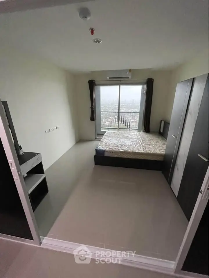 Modern bedroom with large window and balcony view in a high-rise apartment.