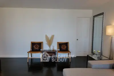Modern living room with stylish chairs, elegant decor, and a large mirror enhancing space.