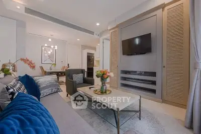 Modern living room with stylish decor and open layout, featuring a cozy seating area and wall-mounted TV.