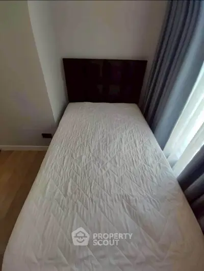 Cozy bedroom with single bed and elegant curtains, perfect for a peaceful retreat.