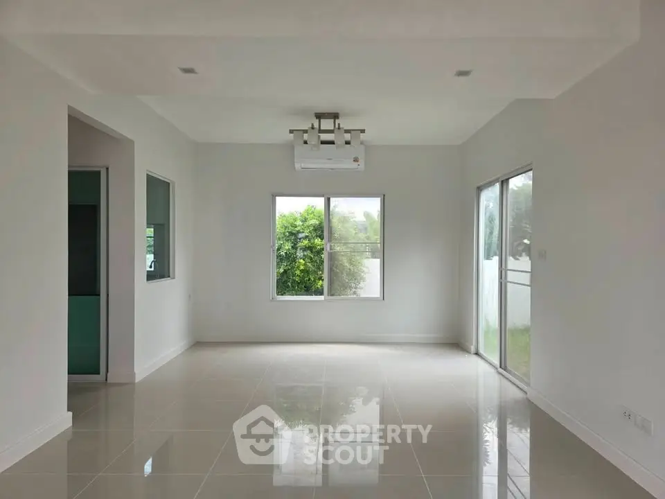 Spacious unfurnished living room with large windows and glossy tiled floor