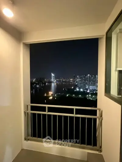 Stunning night view from a high-rise balcony overlooking city skyline and river.
