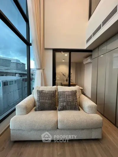 Modern living room with large windows and cozy sofa in high-rise apartment