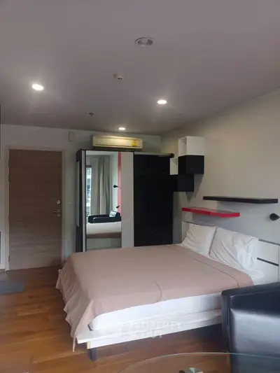 Modern bedroom with stylish decor and ample natural light, featuring a cozy bed and sleek furnishings.