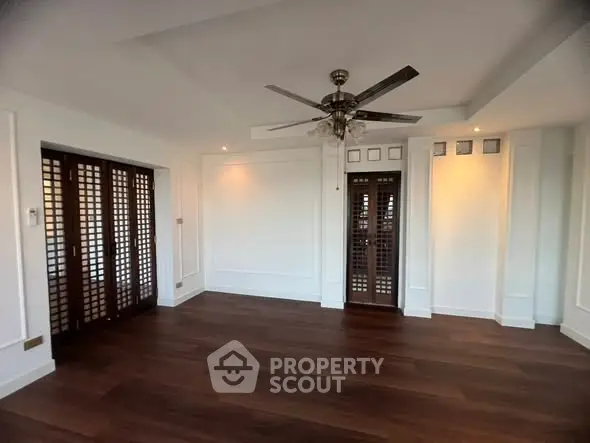 Spacious empty room with elegant wooden flooring and ceiling fan