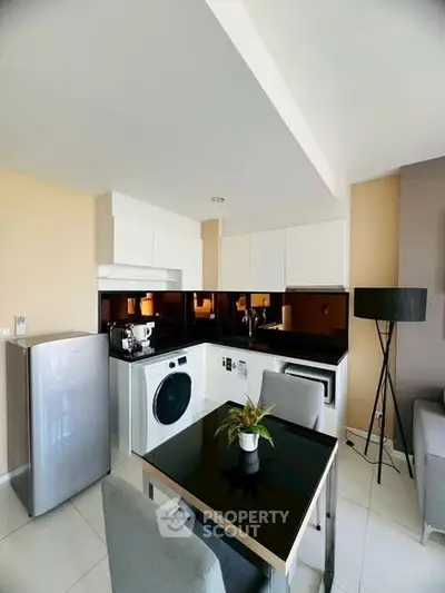 Modern kitchen with sleek appliances and dining area in stylish apartment.