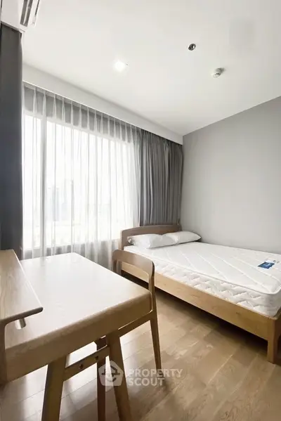 Modern minimalist bedroom with wooden furniture and large window for natural light.