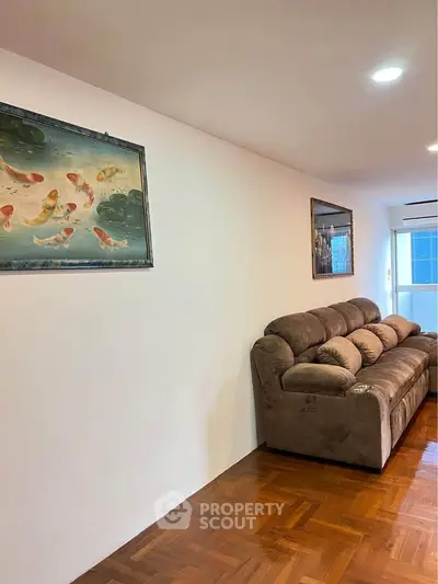 Spacious living room with cozy brown sofa and elegant wooden flooring.