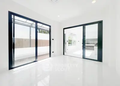 Bright and spacious modern living room with large glass doors and sleek white flooring.