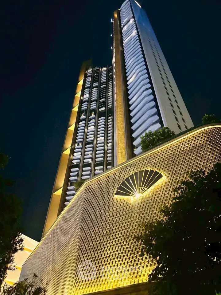 Stunning night view of a modern high-rise building with unique architectural design and illuminated facade.
