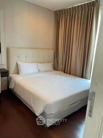 Cozy bedroom with elegant curtains and plush bedding in a modern apartment.