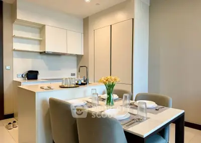 Modern kitchen with dining area, featuring sleek cabinetry and elegant table setting.