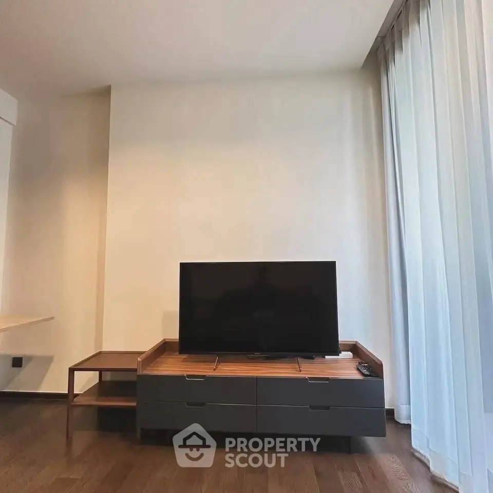 Modern living room with sleek TV stand and floor-to-ceiling curtains, showcasing minimalist design.
