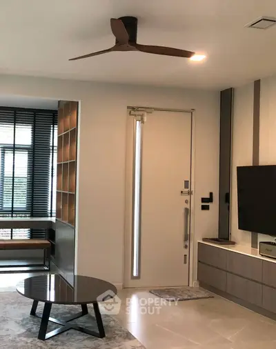 Modern living room with sleek furniture and stylish ceiling fan, featuring a contemporary design and natural light.
