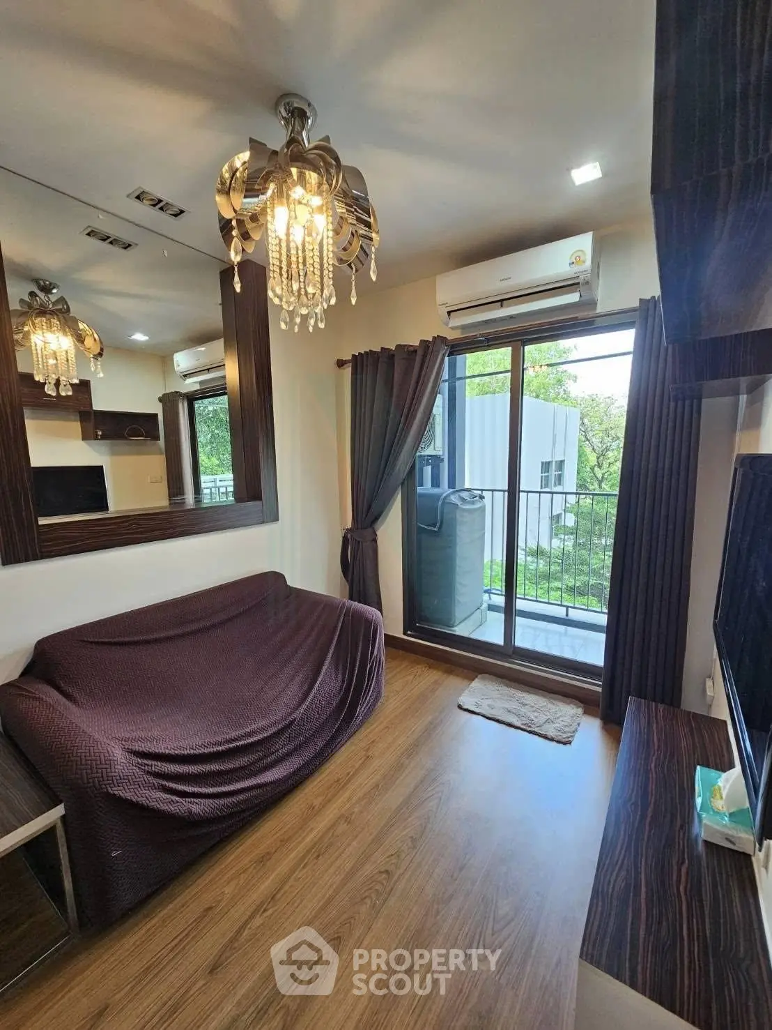 Chic living room with elegant chandelier and balcony view, perfect for modern urban living.