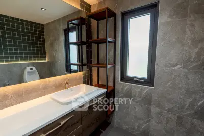 Modern bathroom with sleek sink, stylish tiles, and ample natural light.