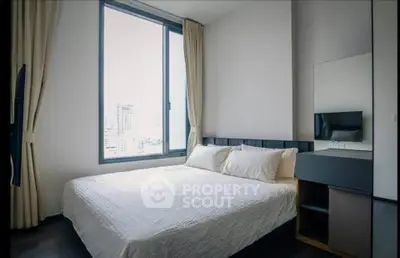 Modern bedroom with large window and city view, featuring a cozy bed and sleek furniture.