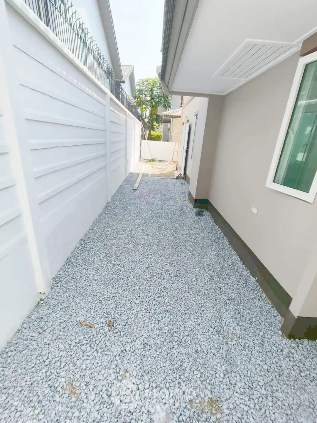 Modern residential exterior with gravel pathway and secure fencing