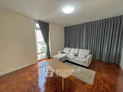Spacious living room with parquet flooring and modern sofa in a bright apartment.