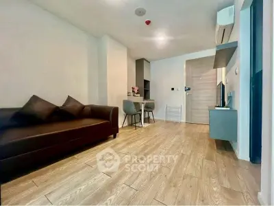 Modern living room with wooden flooring, stylish sofa, and compact dining area in a cozy apartment.