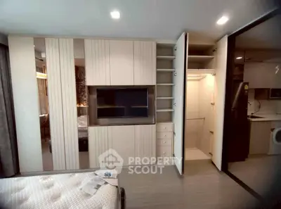 Modern bedroom with built-in storage and sleek design, featuring a TV and open closet space.