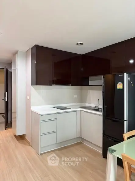 Modern kitchen with sleek cabinetry and black refrigerator in a stylish apartment.