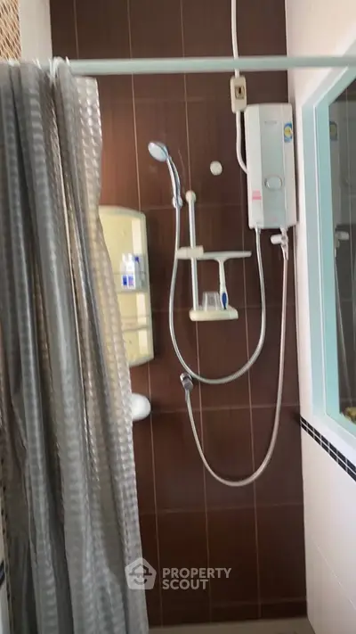 Modern bathroom with shower and water heater, featuring sleek brown tiles and a stylish curtain.