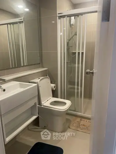 Modern bathroom with glass shower and sleek fixtures in contemporary apartment.