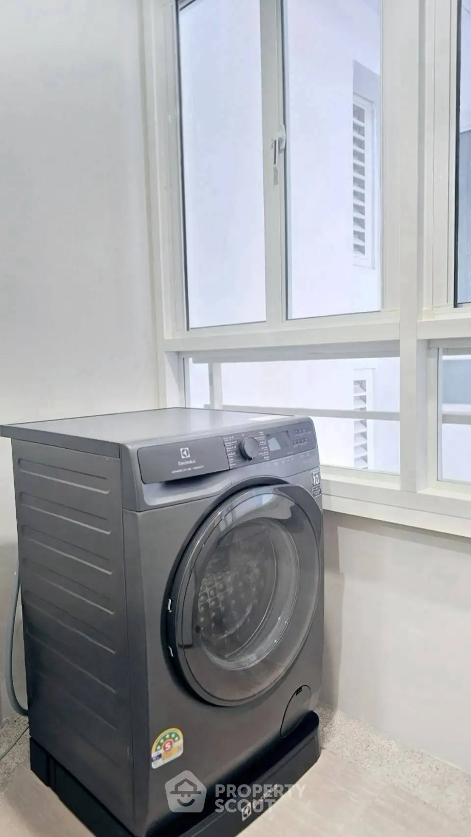 Modern laundry area with sleek washing machine and large window for natural light.