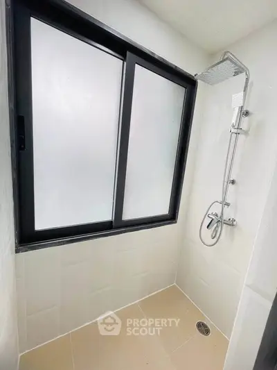 Modern bathroom with sleek shower and frosted window for privacy.