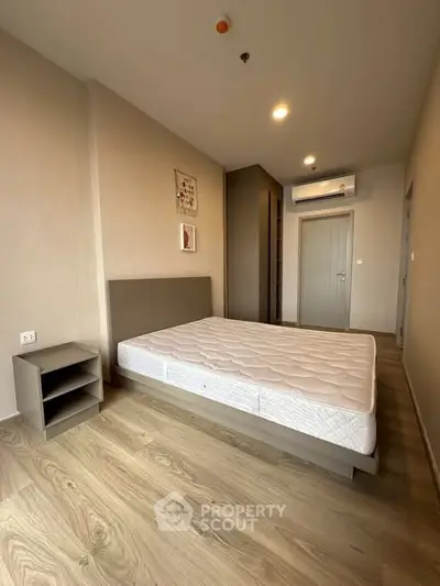 Spacious bedroom with modern design, featuring a comfortable bed and sleek wooden flooring.