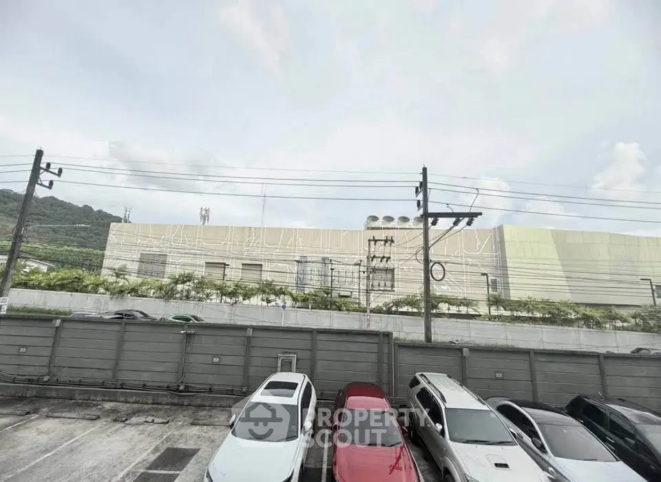 Spacious parking area with multiple vehicles in front of a large industrial building.