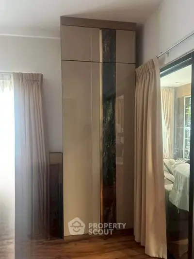 Elegant modern wardrobe in a stylish bedroom with natural light and wooden flooring.