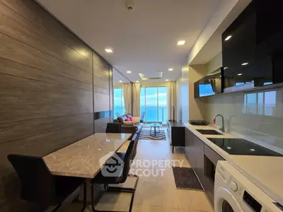 Modern open-layout kitchen and living room with ocean view, sleek furnishings, and natural light.