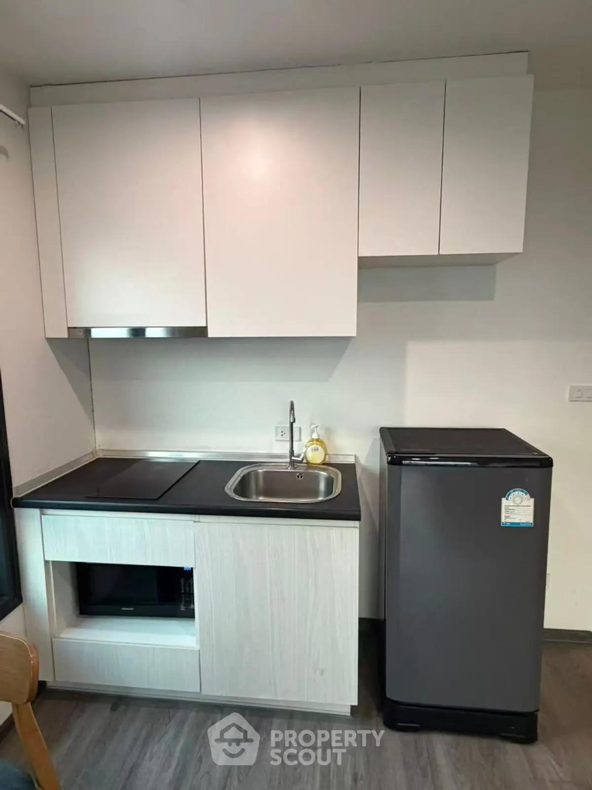 Modern compact kitchen with sleek cabinetry and mini fridge, perfect for urban living.