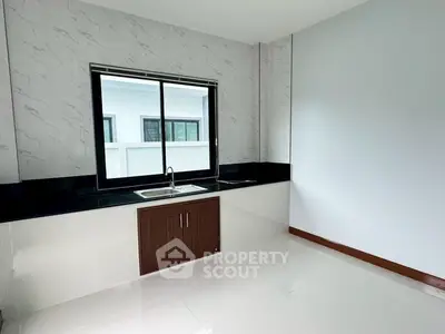 Modern kitchen with sleek design and large window for natural light.