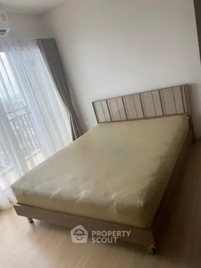 Cozy bedroom with natural light and modern furnishings in a high-rise apartment.