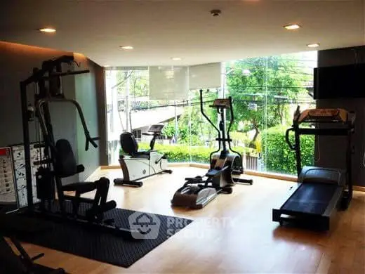 Modern gym with large windows and exercise equipment in a residential building.