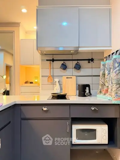 Modern kitchen with sleek cabinetry, microwave, and stylish backsplash, perfect for culinary enthusiasts.