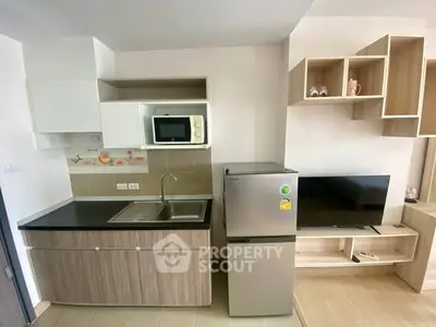 Modern compact kitchen with microwave, fridge, and TV in stylish apartment