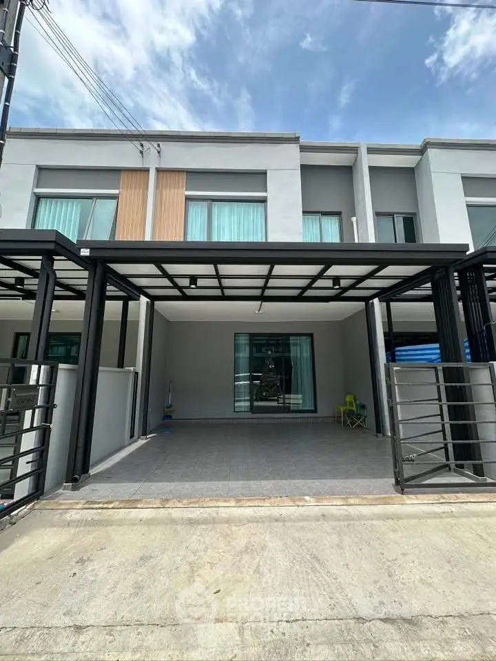 Modern townhouse exterior with sleek design and spacious driveway under a clear blue sky.