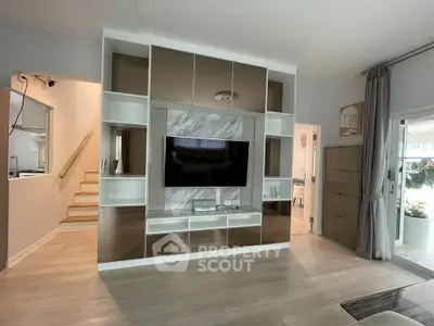 Modern living room with sleek entertainment center and large TV, featuring stylish decor and open layout.